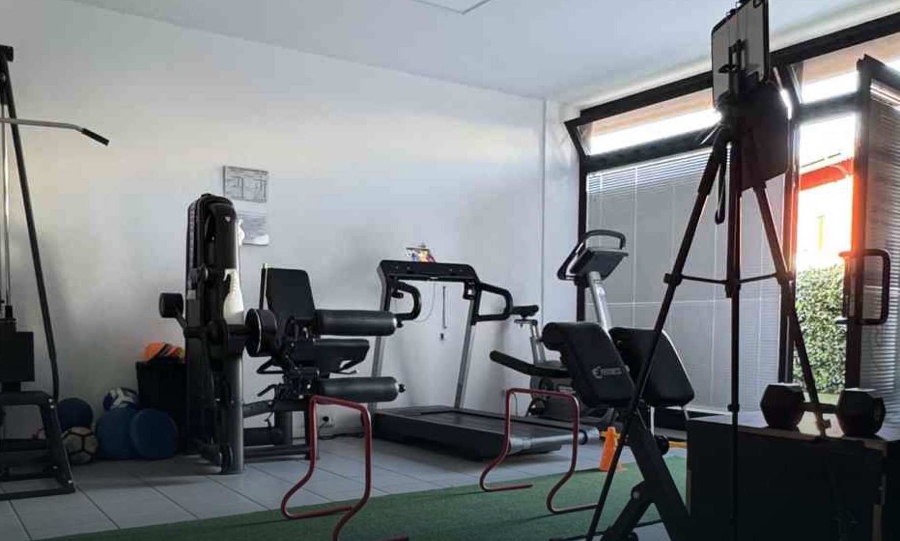 Palestra dello studio con macchine, tapis roulant, ostacoli e treppiede per l'analisi video